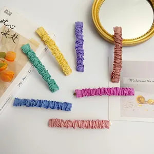Macro detail of assorted pleated fabric hair clips in vibrant candy colors and soft textures