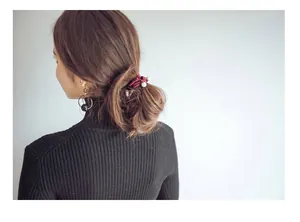 Close-up of pearl hair tie and metal hoop earring worn with elegant black knitwear