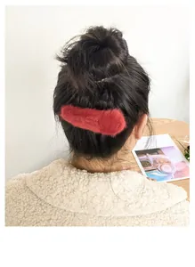 Detail of red plush faux fur hair clip accessory worn on a stylish female updo