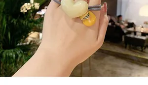 Detailed shot of elastic hair tie featuring yellow heart and round bead charms on wrist
