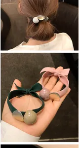 Détail de l'élastique à cheveux avec grande perle acrylique et breloque en métal mat