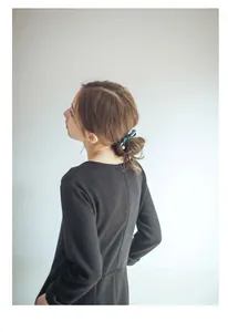 Detailed view of elegant dark green silk bow hair tie with large white pearl on model