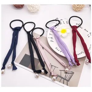 Detail of long ribbon hair ties with large pearls in navy, black, pink, purple, and red