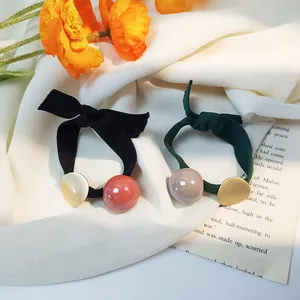 Détail d'élastiques à cheveux avec perles acryliques et breloques dorées sur soie
