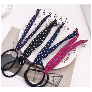 Close-up of polka dot hair ties with ribbon bows and pearls on a stylish background