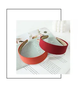 Detail of wide fabric headbands in burgundy and coral orange colors on a magazine