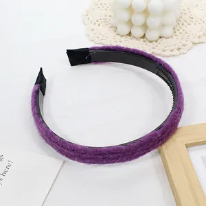 Détail d'un serre-tête tricoté violet avec dents antidérapantes sur un fond de tissu blanc
