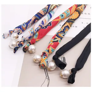 Detailed view of silk hair scrunchies with bohemian patterns and white pearl charms
