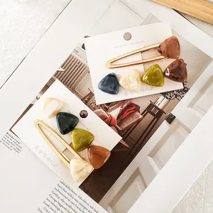 Detail of elegant gold metal hair clips with colorful marble texture resin triangles