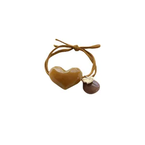 Brown elastic hair tie with caramel heart pendant and engraved gold metal charm