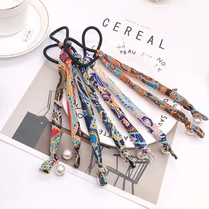 Floral print hair scrunchies with long silk ribbons and pearls on a flat lay background