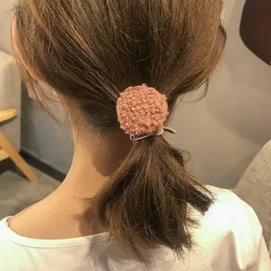 Plüschiger Haargummi mit staubrosa Bommel in der Rückansicht am Haar gezeigt