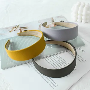 Three minimalist wide fabric headbands in yellow and grey stacked on a magazine