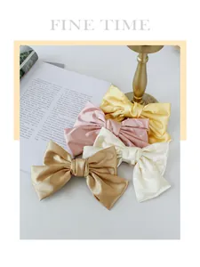 Close-up of elegant satin bow hair clips in champagne, pink, white, and yellow colors