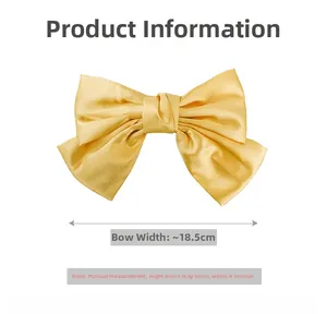 Detail view of a large 18.5cm yellow satin bow clip with a smooth glossy finish
