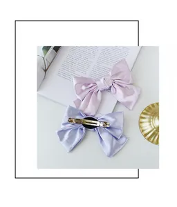 Detailed back view of lavender and blue satin bow hair clips with silver metal spring clips