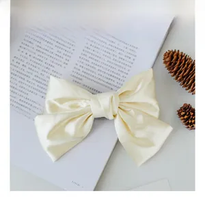 Close-up of champagne gold satin bow hair clip with smooth glossy texture and elegant finish