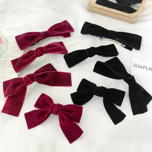 Velvet bow hair clips in wine red and black on white fabric with minimalist accessories