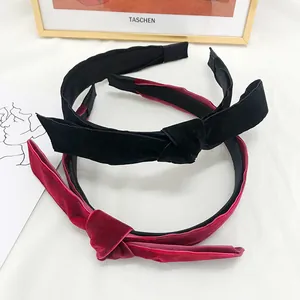 Detail of elegant black and burgundy velvet knotted headbands on a decorative white surface