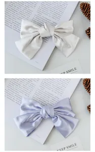 Close-up of cream and lilac satin bow hair clips with elegant silk texture