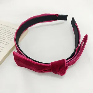 Detail of burgundy velvet headband with knotted bow on white textured background