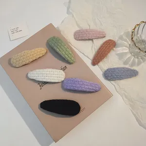 Detail showing seven colorful knitted hair clips with woven texture in a pastel setting