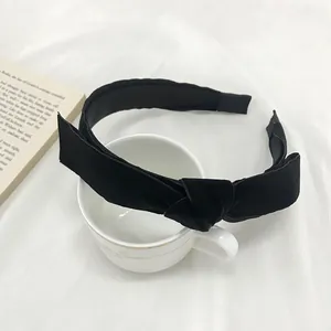 Elegant black velvet knotted headband for women on aesthetic white fabric background