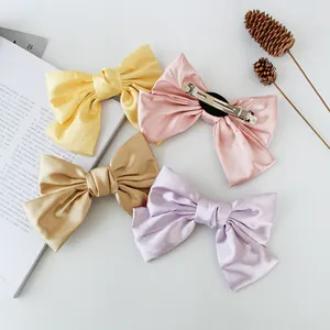 Four-piece set of large satin bow hair clips in pastel colors with metal spring fasteners