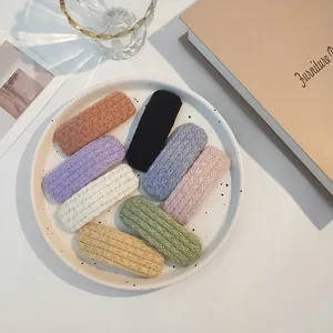 Flat lay of 8 colorful knitted hair clips on a white ceramic plate for girls
