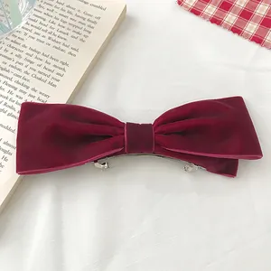 Close-up of velvet bow hair clip in wine red on an open book for vintage aesthetic