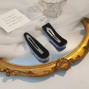 Detail of purple knitted BB hair clips on soft white fabric with vintage mirror background