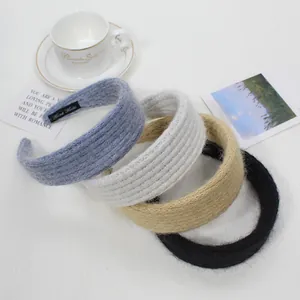 Dettaglio di quattro cerchietti in maglia blu, grigi, beige e neri con etichetta Hand Made