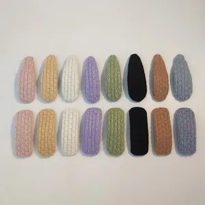 Flat lay of 16 colorful knitted drop-shaped and rectangular BB hair clips in various hues