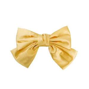 Elegant large yellow satin bow hair clip with silky texture on white background