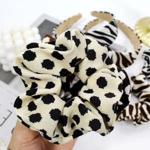 Detailed view of beige knitted polka dot scrunchie with soft elastic fabric texture