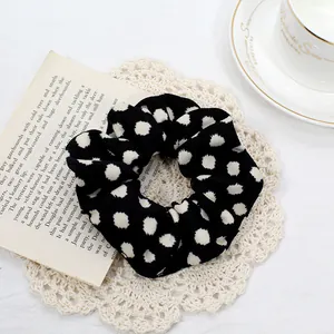 Detail of black and white polka dot scrunchie on lace coaster with coffee cup