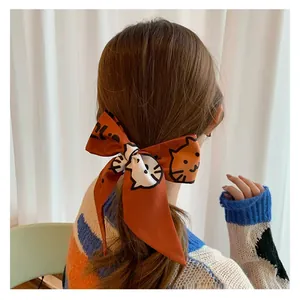 Close-up of a satin ponytail scarf with cat illustration and artistic letters in orange