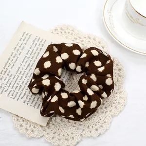 Detail of vintage brown polka dot scrunchie on lace coaster with aesthetic background