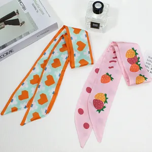 Detail of silk twilly hair scarves in mint heart and strawberry prints on white background