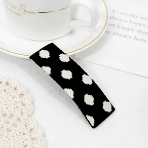 Detailed view of a black and white polka dot fabric hair clip on a decorative background