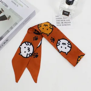 Detail of orange hair ribbon with cute cartoon cat prints and pointed ends for ponytails