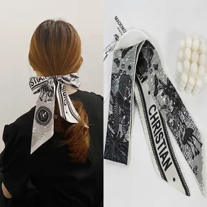Detail of black and white silk hair scarf with retro patterns on a styled background