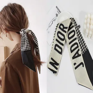 Detail of houndstooth silk scarf headband with elegant letter print in black and white
