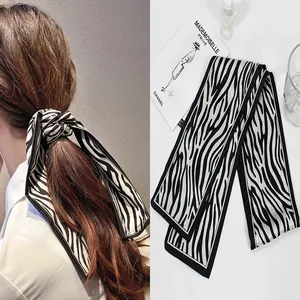 Detailed macro view of zebra print satin hair scarf featuring elegant black piping edges