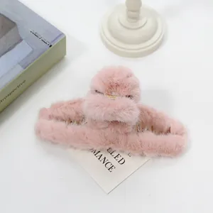 Detalle de pinza para el pelo de peluche rosa con resorte de metal en mesa