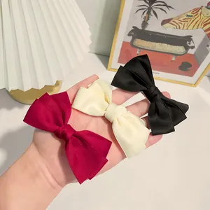 Three-piece set of elegant layered bow hair clips in burgundy, cream white, and black colors