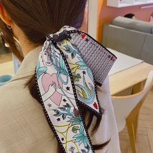 Detail view of a French retro silk hair scarf with colorful artistic illustrations on hair