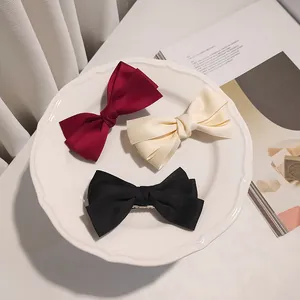 Three-piece layered satin bow hair clips in wine red, cream white, and classic black