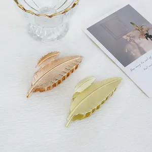 Dettaglio di due mollette per capelli in metallo a forma di foglia in oro e oro rosa lucido