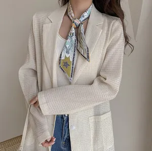 Close-up of cream pleated blazer fabric and a narrow silk scarf with tarot prints